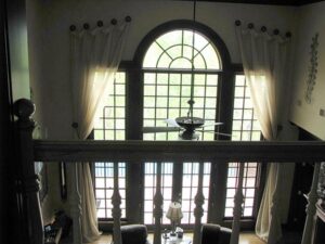 Elegant living room with tall arched windows and sheer curtains.